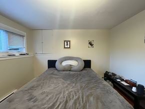 Victoria apartment for rent - A bed with a grey comforter and a white pillow is in the center of the room.