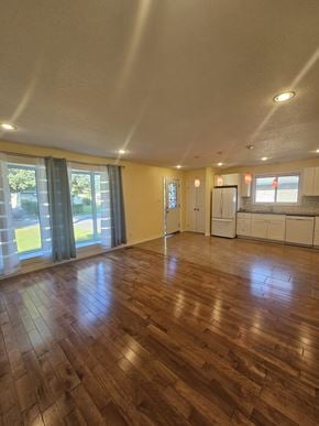 London apartment for rent - A room with wooden floors and a kitchen area in the background.