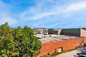 Washington apartment for rent - A view of a building with a parking lot in front and trees on the left.
