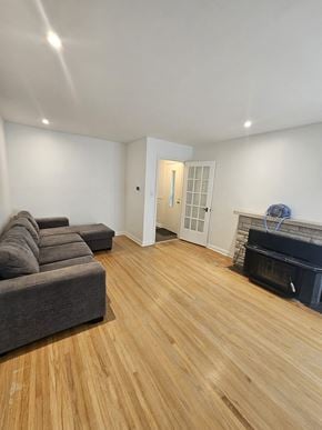 London apartment for rent - A grey couch sits in a room with wooden flooring and a fireplace.