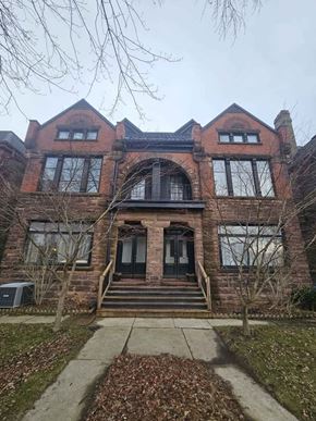 London apartment for rent - A large red brick house with a black front door and steps leading up to it.