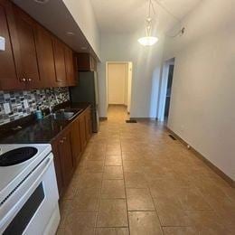 London apartment for rent - A kitchen with a white stove top oven and a tiled floor.