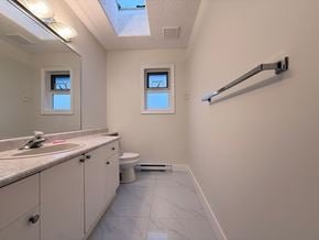 Victoria apartment for rent - A bathroom with a toilet, sink, and mirror.