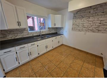 Los Angeles apartment for rent - A kitchen with white cabinets and a stone wall.