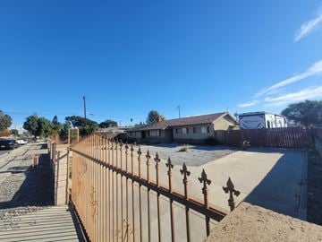 Ontario house for rent - A brown fence with pointed tops stands in front of a house.