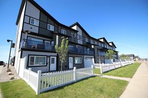 Regina apartment for rent - A white picket fence separates a row of modern townhouses.