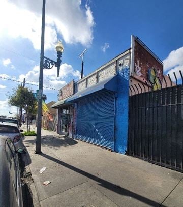 Los Angeles apartment for rent - A blue building with a closed shutter and a black gate.