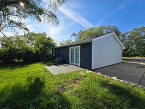 Gary house for rent - a small black and white house with a driveway and a garage door