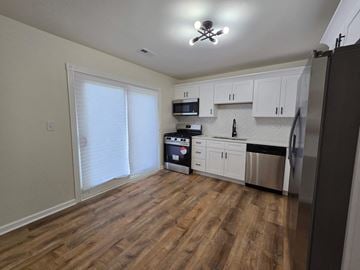 Gary house for rent - a kitchen with white cabinets and stainless steel appliances