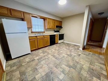 New Albany house for rent - A kitchen with a white refrigerator, wooden cabinets, and a tiled floor.