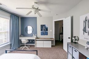 Hubert house for rent - a bedroom with a bed and a desk and a ceiling fan