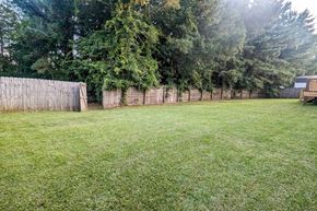 Hubert house for rent - a backyard with a fence and a lawn and trees