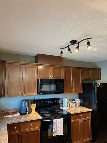 Fort Mcmurray house for rent - A kitchen with wooden cabinets and black appliances.