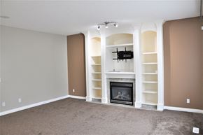 Airdrie house for rent - A living room with a fireplace and a TV mounted above it.