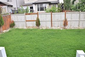 Airdrie house for rent - A backyard with a brown fence and green grass.
