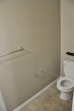 Airdrie house for rent - A white toilet sits next to a shower in a bathroom.