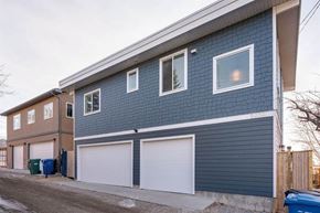 Calgary apartment for rent - A two-story house with a blue exterior and white garage doors.