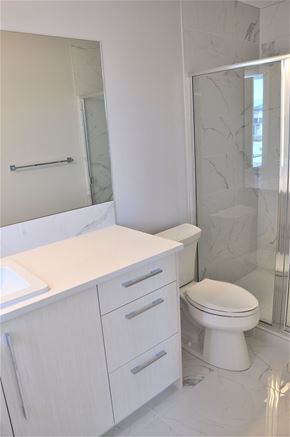 Chestemere house for rent - A white toilet sits next to a walk-in shower.