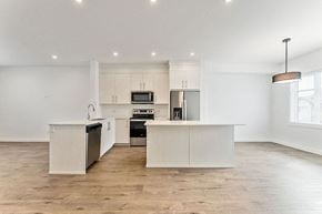 Calgary house for rent - a white kitchen with a large island in the middle