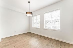 Calgary house for rent - an empty living room with wood floors and two windows