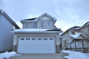 Calgary house for rent - A house with a garage and a driveway covered in snow.