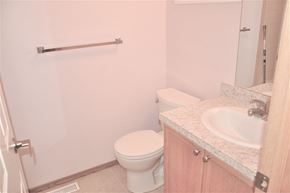 Calgary house for rent - A white toilet sits in a bathroom next to a sink.