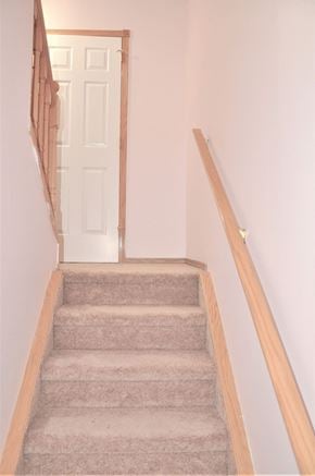 Calgary house for rent - A staircase with a beige carpet and wooden banister.