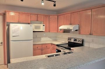Calgary house for rent - A kitchen with a white fridge, microwave, and stove top oven.