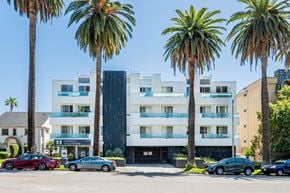 Los Angeles apartment for rent - a white building with palm trees and cars parked in front of it