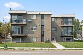 Calgary house for rent - A grey apartment building with a black door and windows.