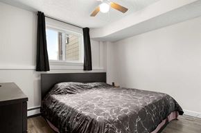 Calgary house for rent - A bedroom with a bed, nightstand, and window with black curtains.
