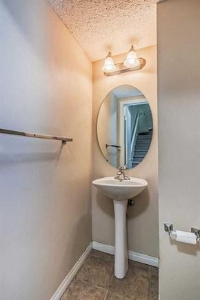 Calgary house for rent - A bathroom with a sink, mirror, and toilet paper holder.