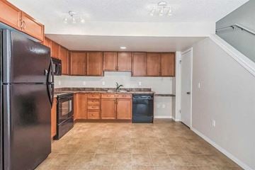 Calgary house for rent - A kitchen with a black refrigerator and wooden cabinets.