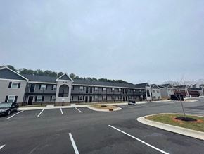Youngsville apartment for rent - A parking lot in front of a building with a grey roof.