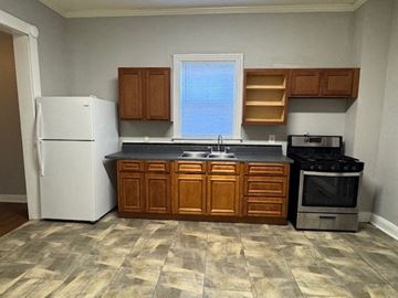 Louisville apartment for rent - A kitchen with a white refrigerator, wooden cabinets, and a black stove top oven.