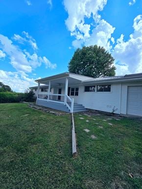 Mayslick house for rent - A house with a white exterior and a porch is surrounded by a grassy yard.
