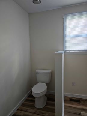 Mayslick house for rent - A white toilet in a small bathroom with wood flooring.