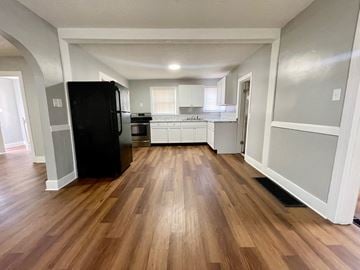 Louisville house for rent - A kitchen with a black fridge and wooden floors.