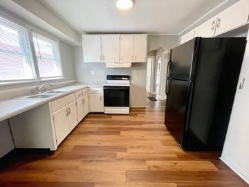 Louisville house for rent - A kitchen with a black refrigerator and wooden floors.