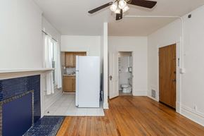 Denver apartment for rent - A white fridge in a room with wooden floors and a ceiling fan.