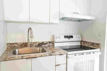 Miami apartment for rent - a kitchen with white cabinets and a sink and a stove