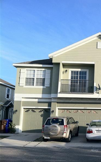 Kissimmee house for rent - A two-story house with a garage and two cars parked in front.