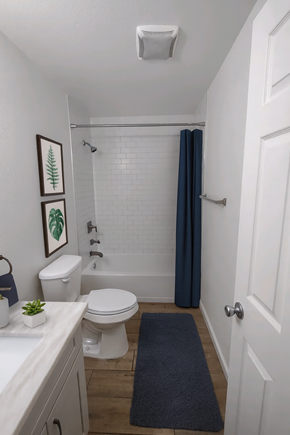 San Jose apartment for rent - A white toilet with a white sink and a white bathtub with a blue shower curtain.