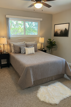 San Jose apartment for rent - A bedroom with a bed, two lamps, a fan, and a rug.
