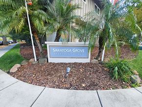 San Jose apartment for rent - A sign for Saratoga Grove Apartments is surrounded by plants and rocks.