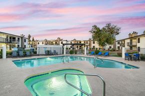 Phoenix apartment for rent - A swimming pool surrounded by chairs and buildings.