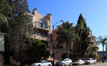 Long Beach apartment for rent - A white car is parked in front of a tan building with a balcony.