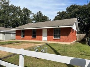 Gulfport house for rent - A red brick house with a white fence in front.