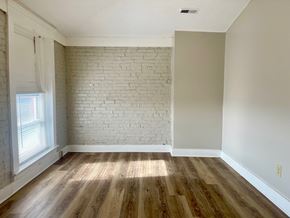 Louisville apartment for rent - A room with wooden floors and a white brick wall.