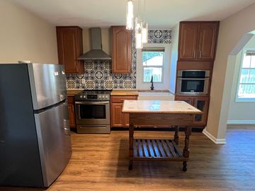 Palatka house for rent - A kitchen with a black fridge and wooden cabinets.